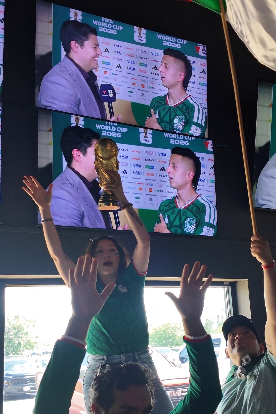 Fans cheering under a wall of TVs during a Mexico World Cup match at SKYBOX