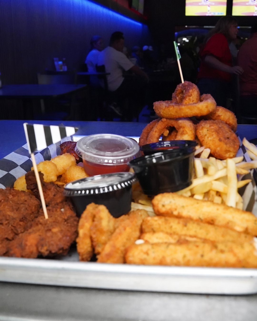 A Skybox platter with fried chicken, onion rings, cheese sticks and fries