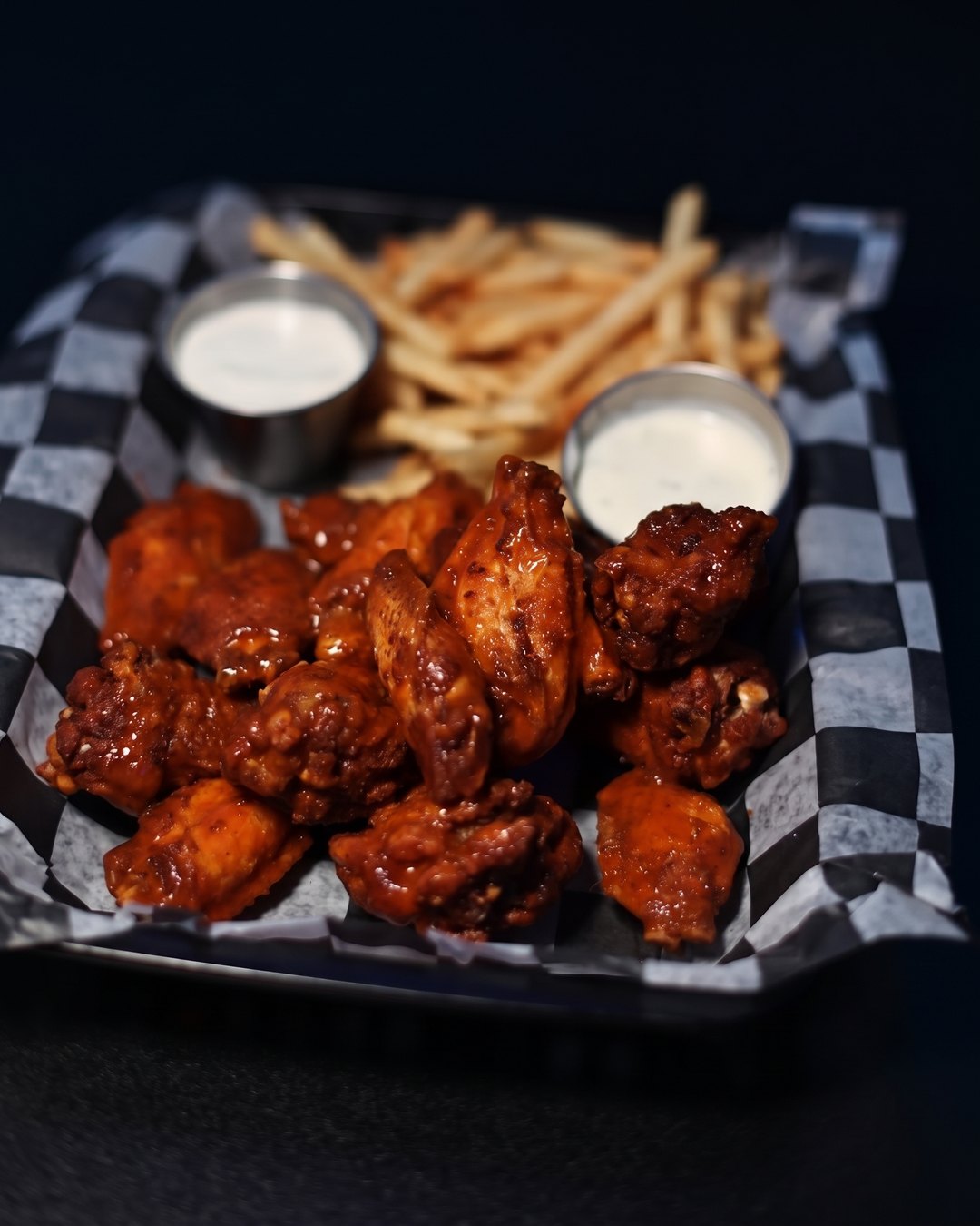 Glazed wings in a checkered basket with fries and ranch